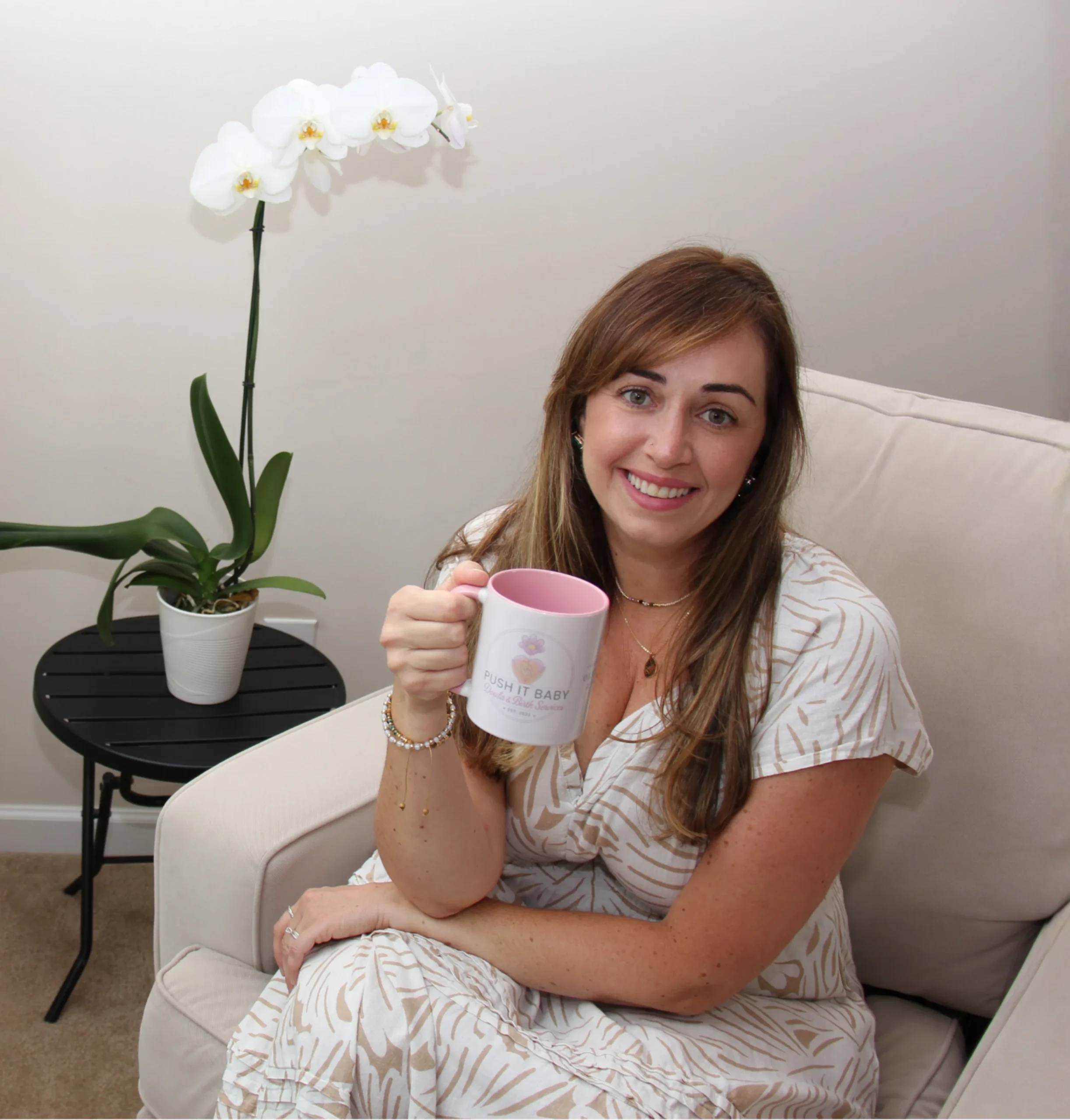 Ana Buzolin smiling on a sofa holding a mug
