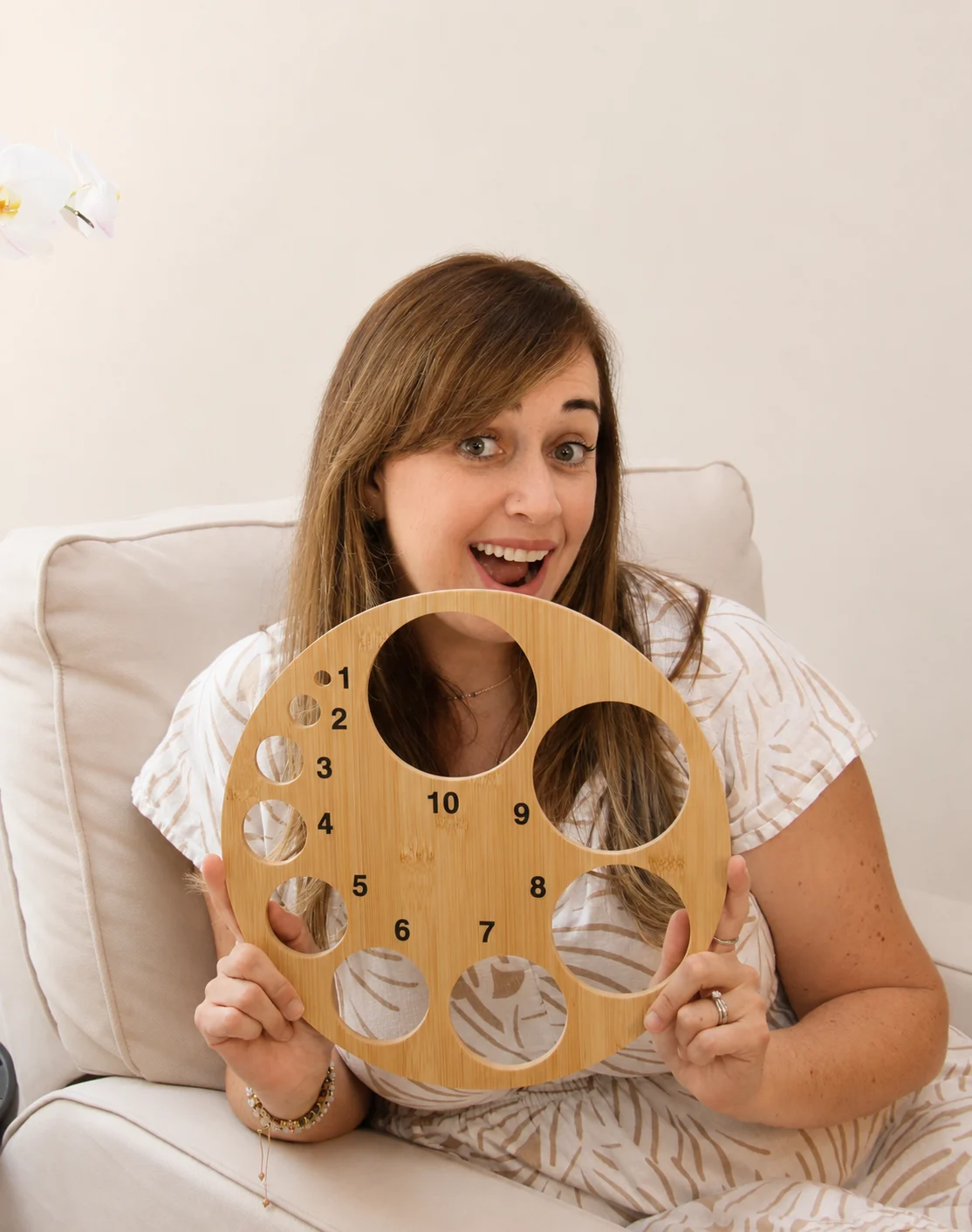 Ana smiling in surprise while holding a wooden board with numbered round openings